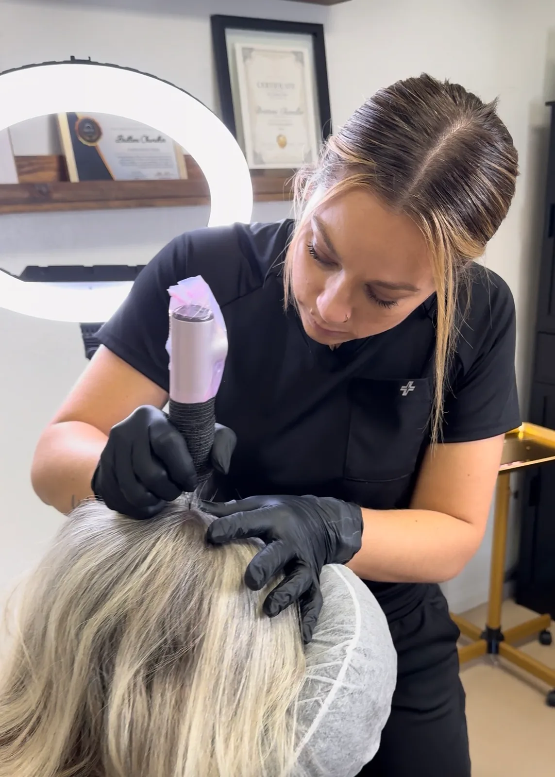 Britteni adding scalp micropigmentation density along a client's part line